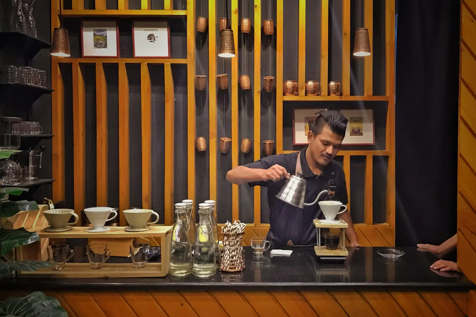 A barista pouring hot water over a coffee filter at the bar of a café in Kathmandu